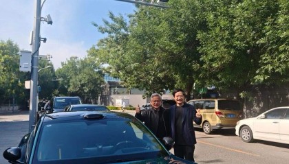 黄仁勋与雷军合影，35度天气仍穿皮衣！两人站在一辆小米汽车前，面带微笑，显得十分亲切